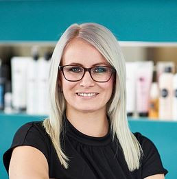 Jane Dobe im Salon am Stadtbad in Halle (Saale) vor einem Regal mit Haarpflegeprodukten