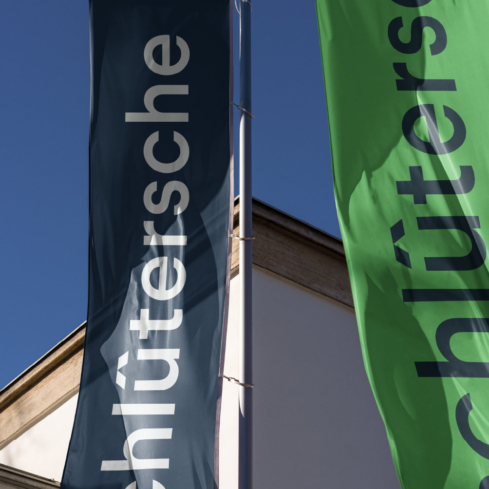 Schlütersche Logo auf Fahnen vor blauem Himmel – Anwendung des Corporate Designs