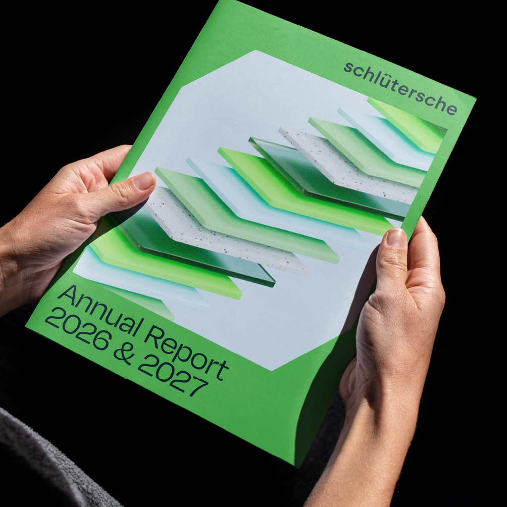 Person hält den Schlütersche Annual Report 2026 & 2027 mit grünem, modernem Design in den Händen