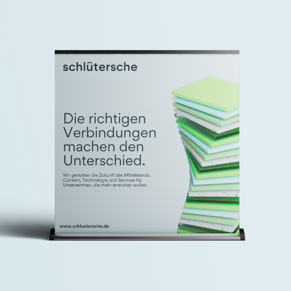Rollup-Display der Schlütersche mit dem Slogan 'Die richtigen Verbindungen machen den Unterschied' und gestapelten grünen Platten