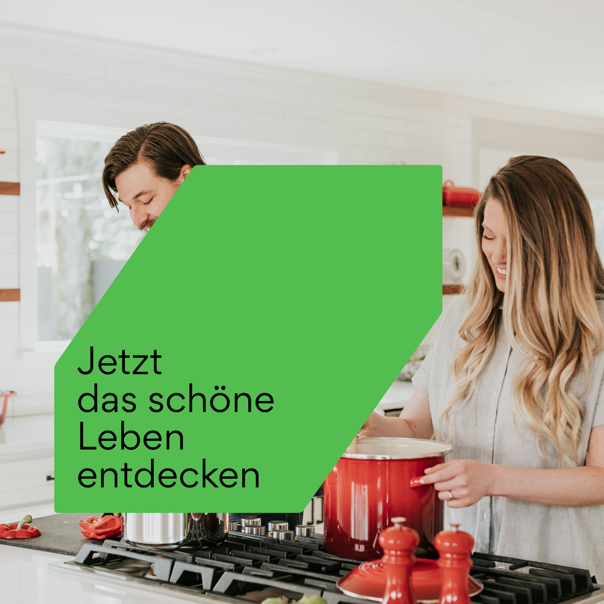 Moderne Küche mit zwei Personen, die gemeinsam kochen, und grünem Formelement mit dem Text 'Jetzt das schöne Leben entdecken' – Brandbase Formensprache