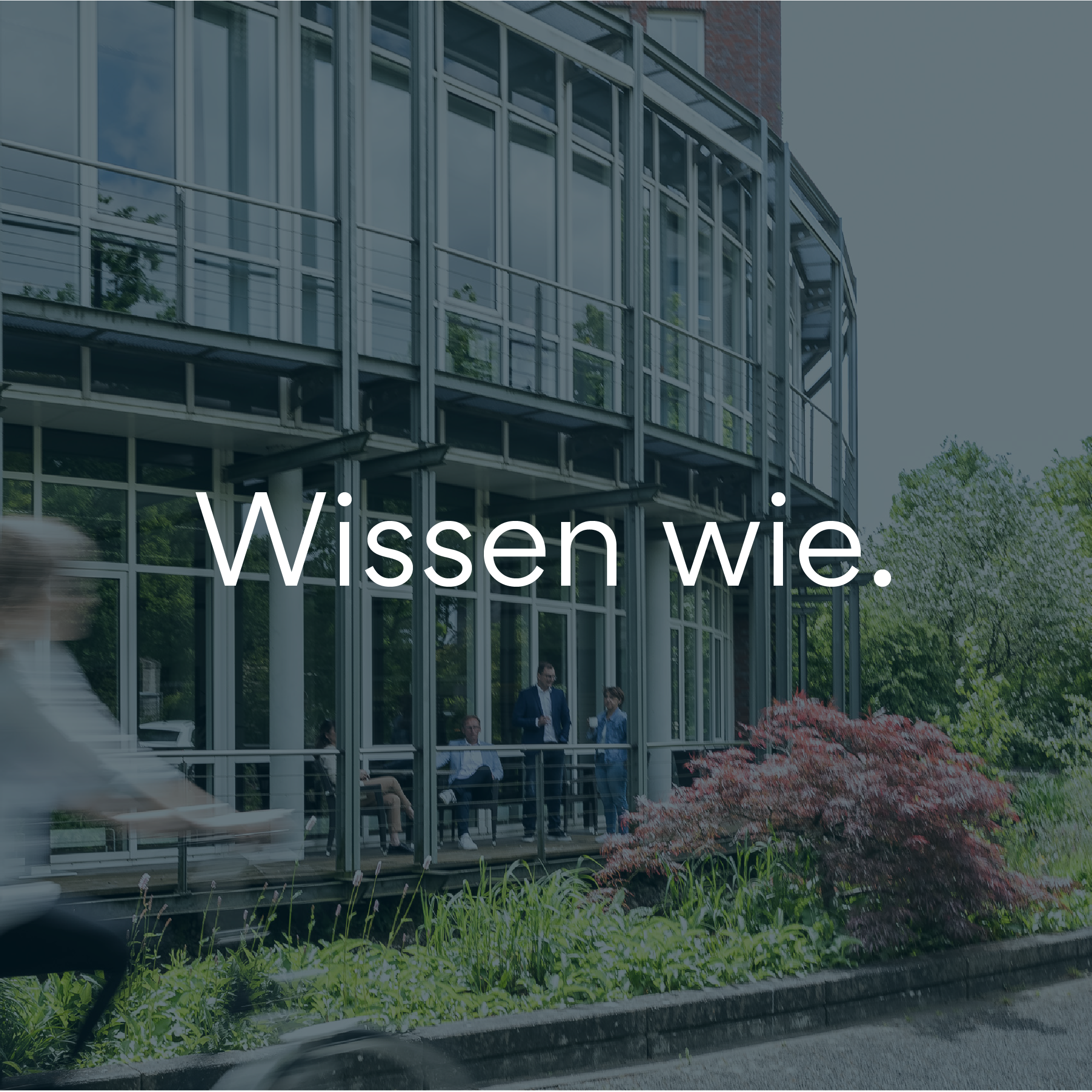 Modernes Bürogebäude mit Glasfassade und dem Claim 'Wissen wie.' im Vordergrund, Beispiel für SC Brandbase Markenauftritt