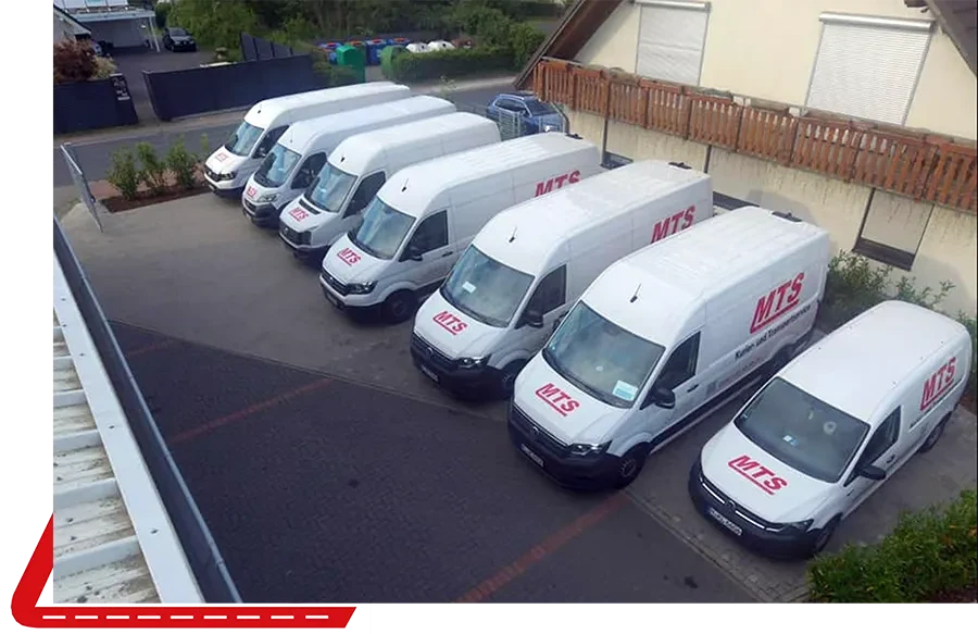 Mehrere weiße Transporter mit MTS-Logo auf einem Firmenparkplatz