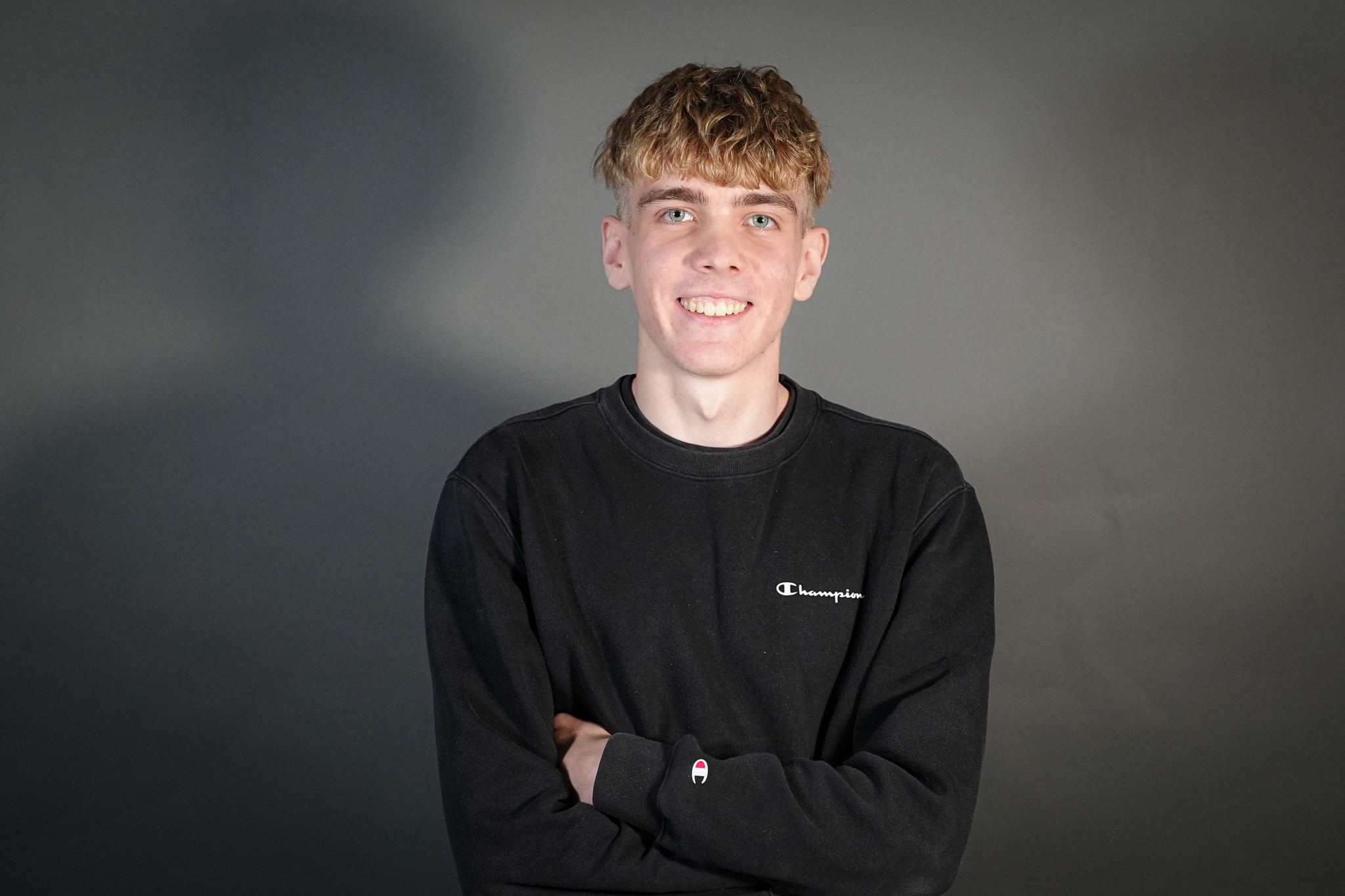 Fynn Gutzler in schwarzem Champion Pullover vor grauem Hintergrund