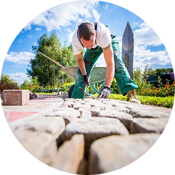 Professionelle Gestaltung von Gärten und Anlagen mit Pflasterarbeiten Gärtner verlegt Pflastersteine in einer Gartenanlage bei sonnigem Wetter