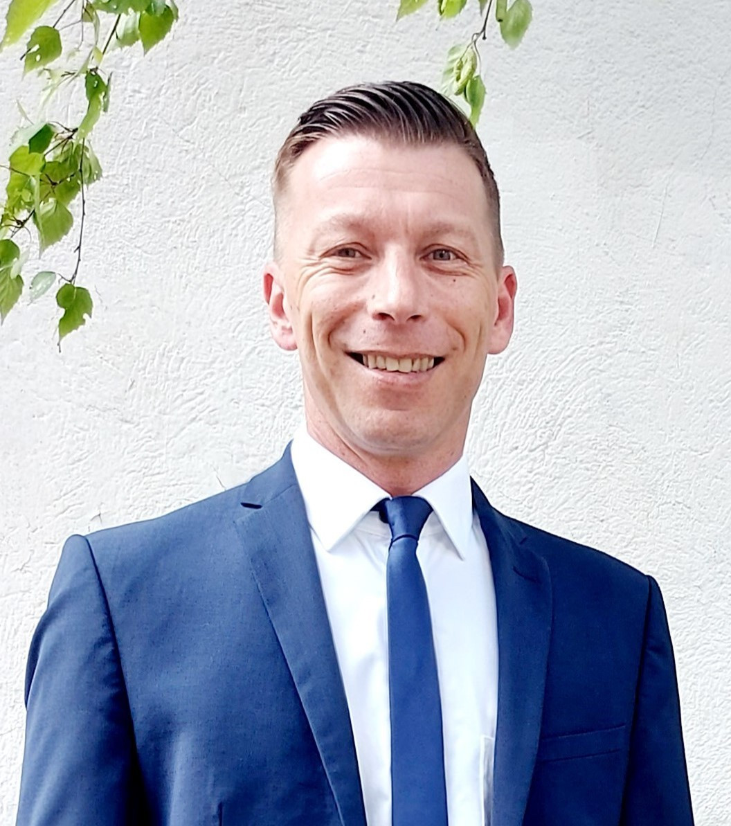 Thomas Herrmann im blauen Anzug vor heller Wand