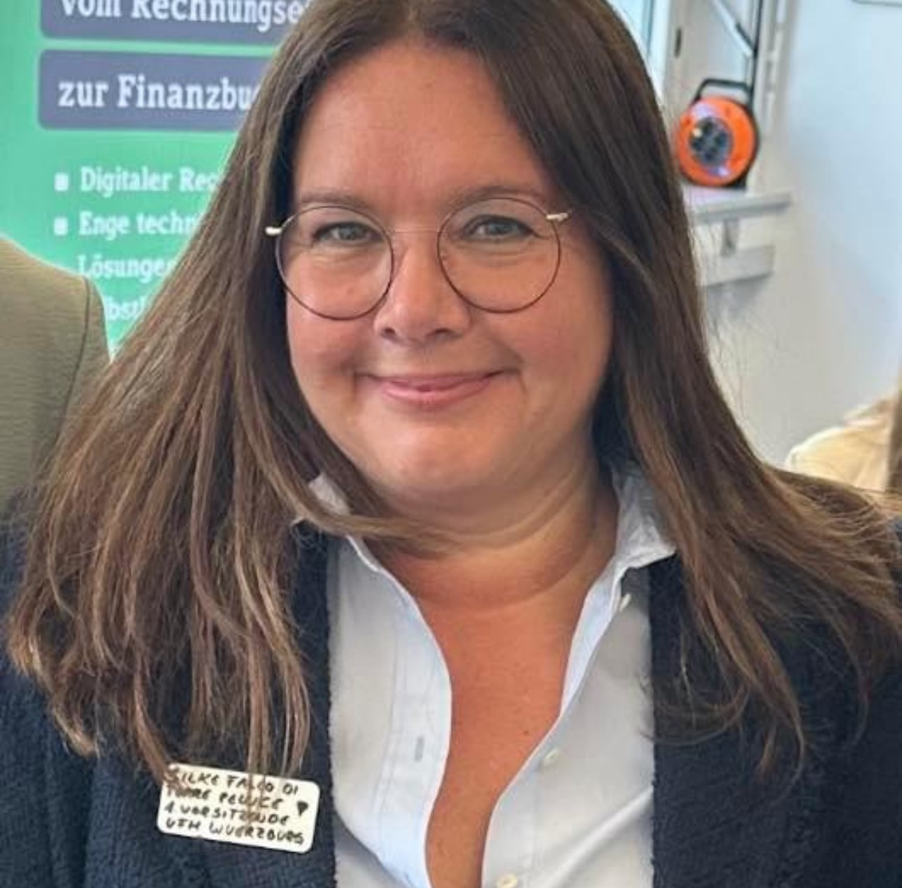 Silke Falco bei einer Veranstaltung, trägt Namensschild und Business-Outfit