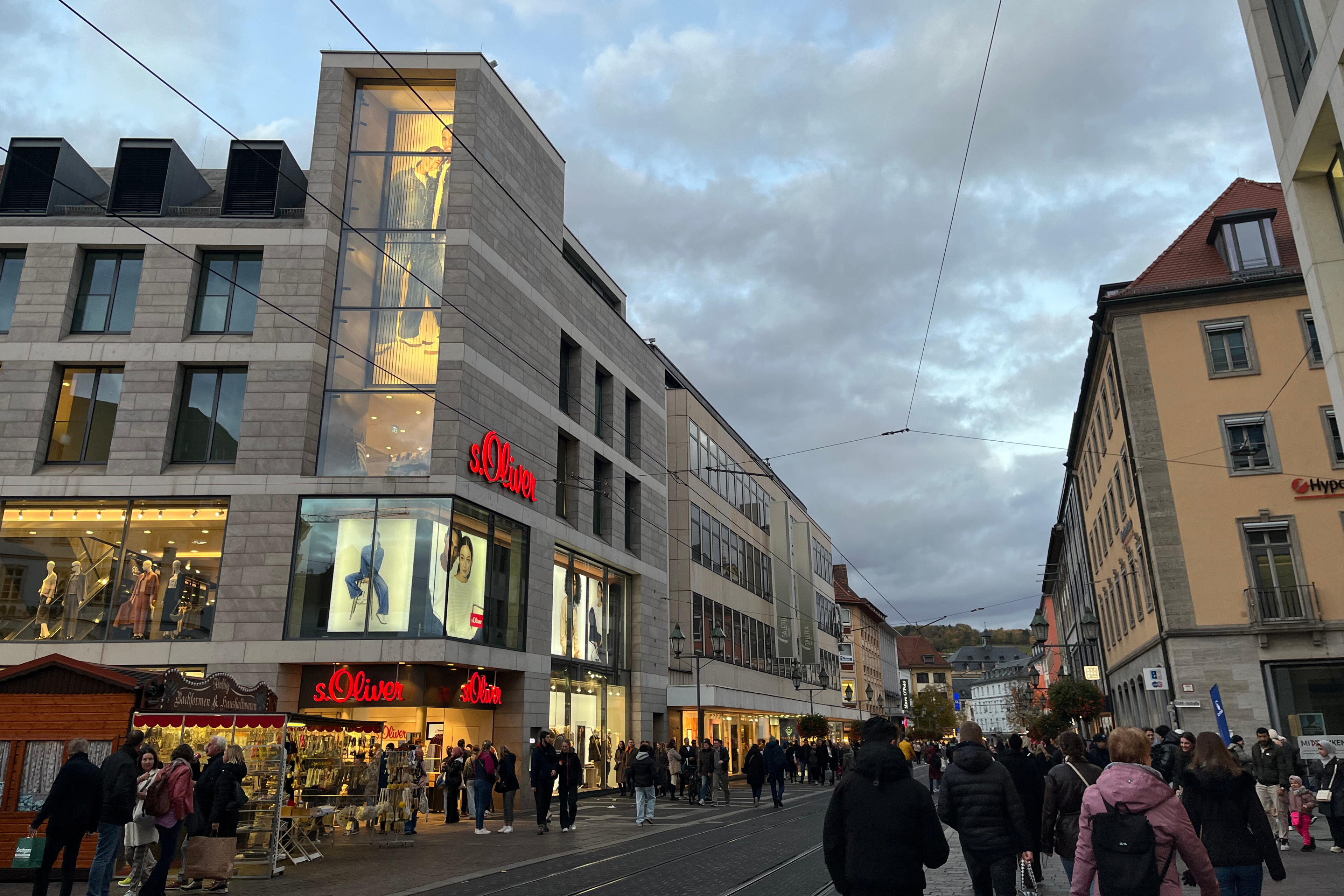 s.Oliver Geschäft in der Innenstadt bei Abenddämmerung mit Passanten s.Oliver Filiale in einer belebten Einkaufsstraße am Abend