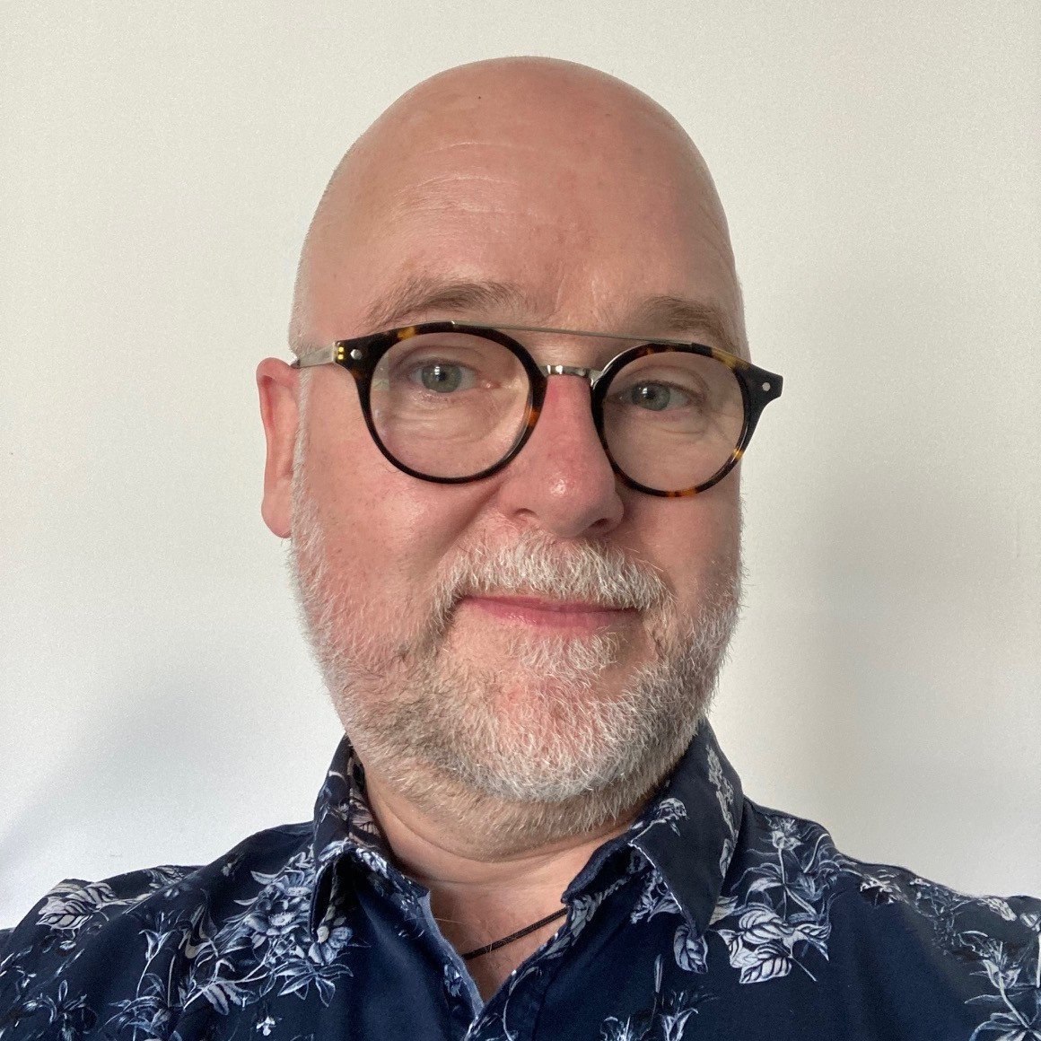 Person mit floralem Hemd vor hellem Hintergrund