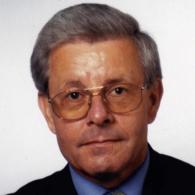 Porträtfoto eines älteren Mannes mit grauen Haaren und Anzug