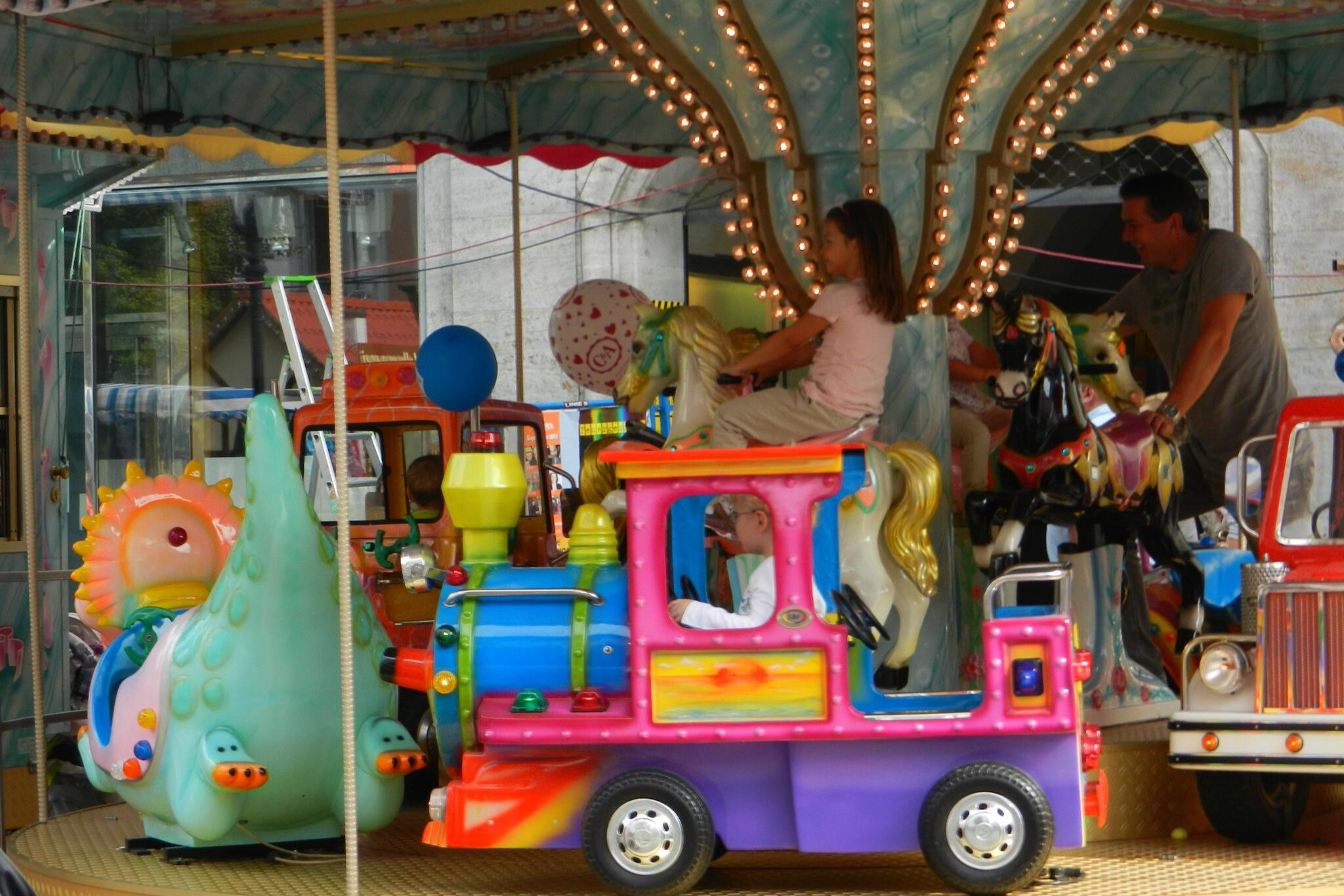 Buntes Kinderkarussell mit Zug und Pferden auf einem Jahrmarkt