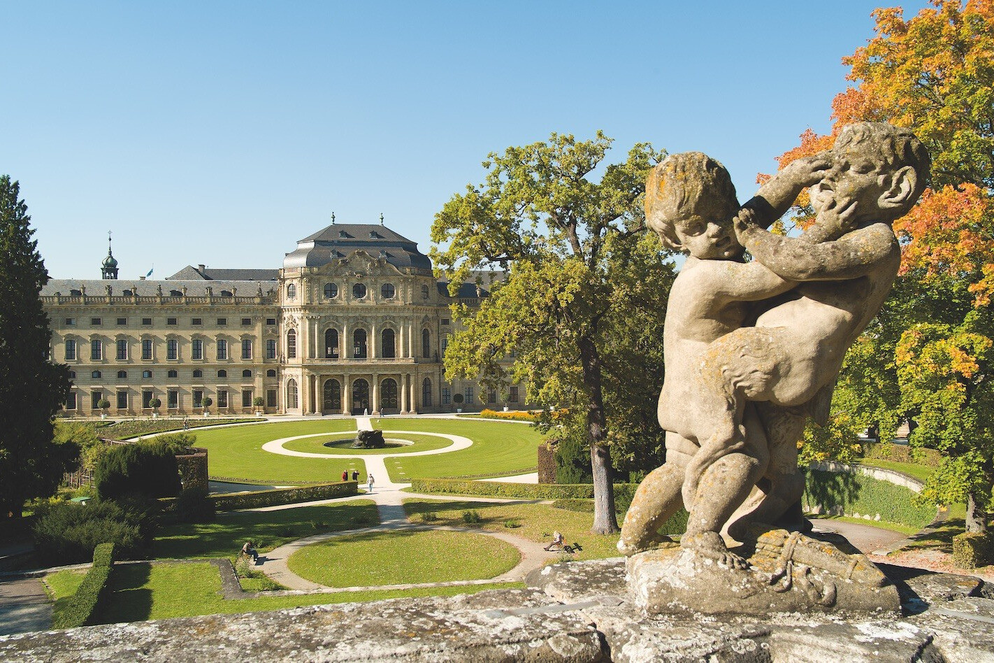 Blick auf die Würzburger Residenz mit Garten und Statue im Vordergrund
