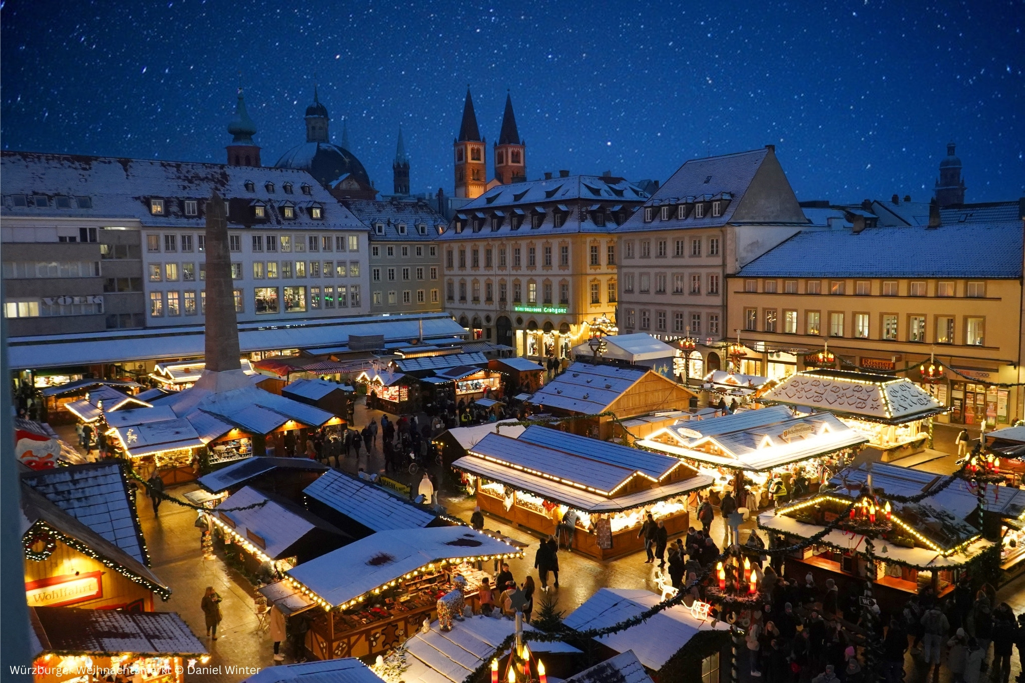 Würzburger Weihnachtsmarkt bei Nacht mit festlich beleuchteten Buden und verschneiten Dächern, fotografiert von Daniel Winter