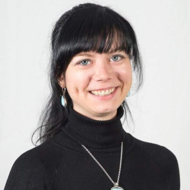 Frau mit schwarzem Rollkragenpullover und Kette mit Anhänger vor hellem Hintergrund