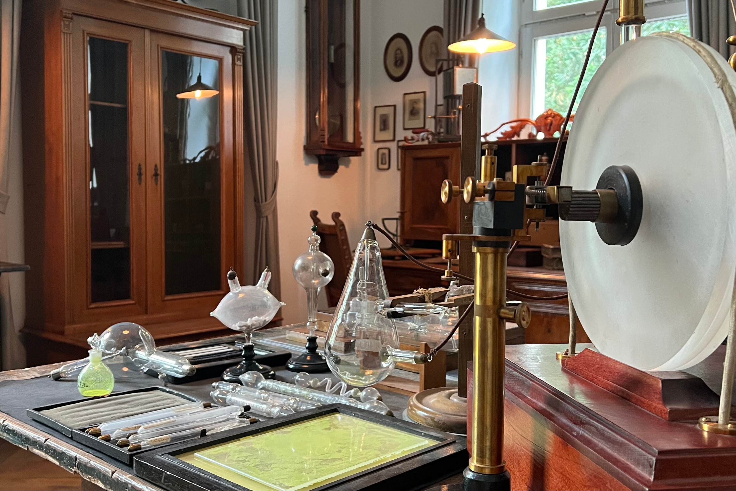 Historisches Physiklabor mit alten wissenschaftlichen Geräten und Glasapparaturen auf einem Holztisch