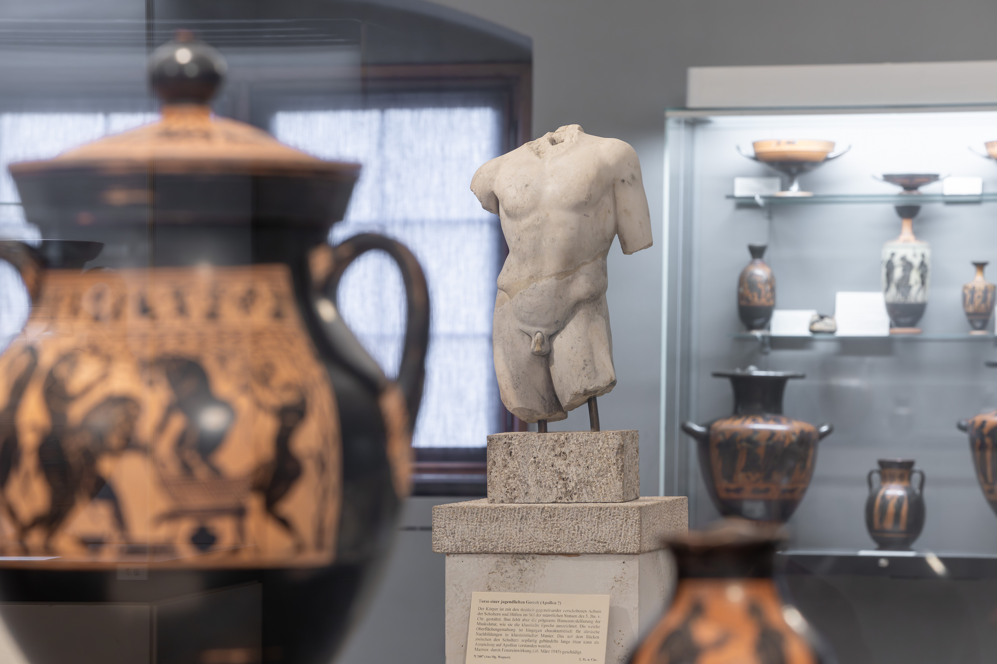Antike Marmorskulptur eines männlichen Torsos und griechische Vasen im Museum, mvwm-230614-071.jpg