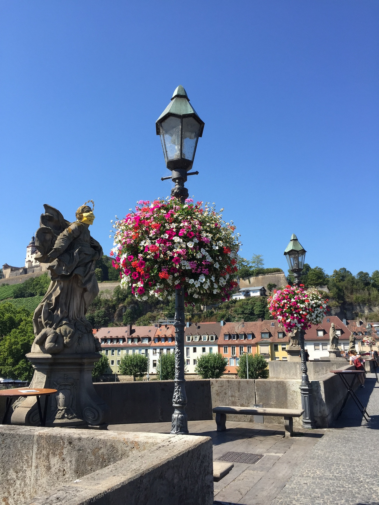 Alte Mainbrücke in Würzburg mit Blumen und Statue bei Sonnenschein
