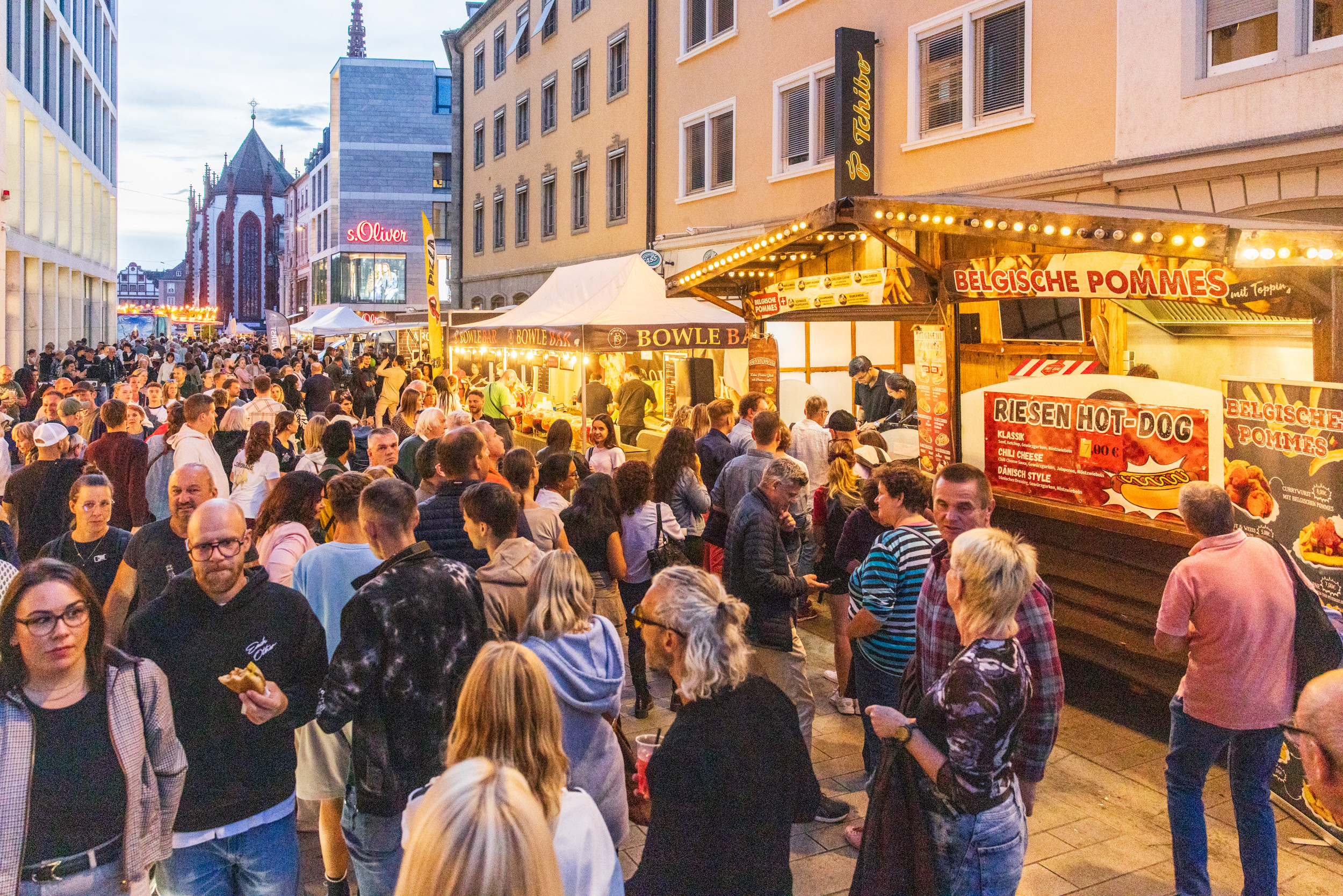 Großes Straßenfest mit Menschenmenge an Essensständen am Abend in einer deutschen Innenstadt