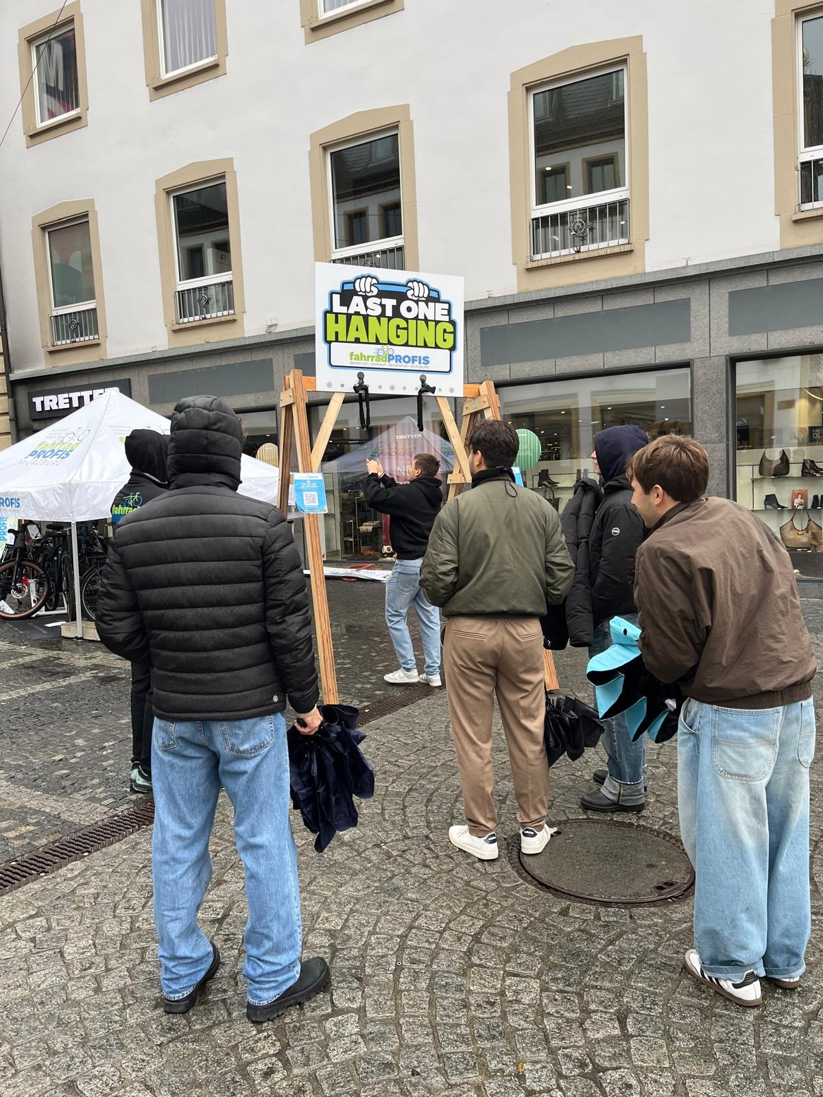 Personen nehmen an der Aktion 'Last One Hanging' von fahrradPROFIS in einer Innenstadt teil