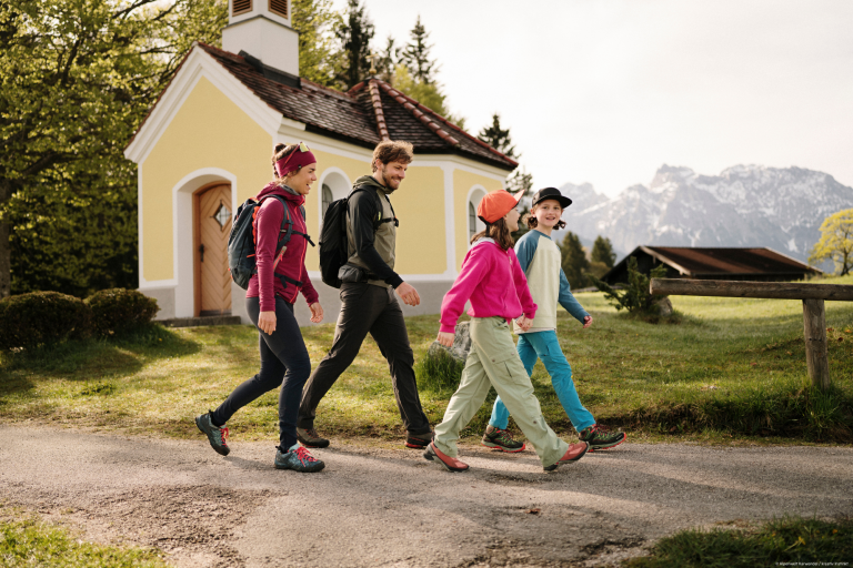 Wandern und Zusammensein: Familie entdeckt gemeinsam die Natur vor einer Kapelle Familie beim Wandern und Entdecken in der Natur gemeinsam unterwegs vor einer kleinen Kapelle