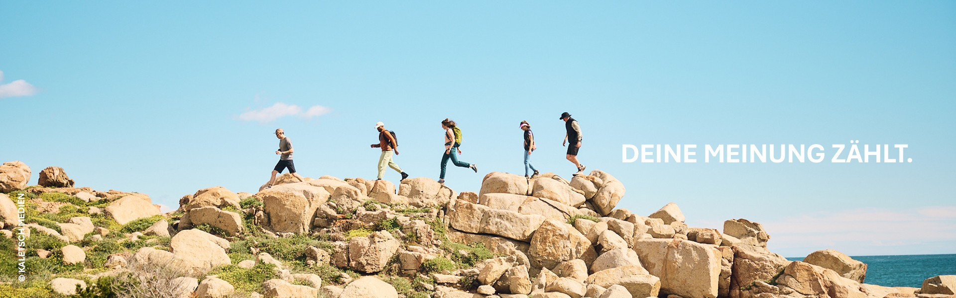 Gruppe von Wanderern auf Felsen unter blauem Himmel