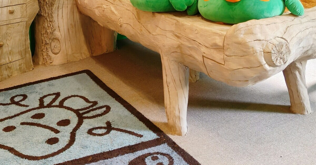 Bunter Teppich im Kinderzimmer neben einem Holzspielmöbel und Kuscheltieren