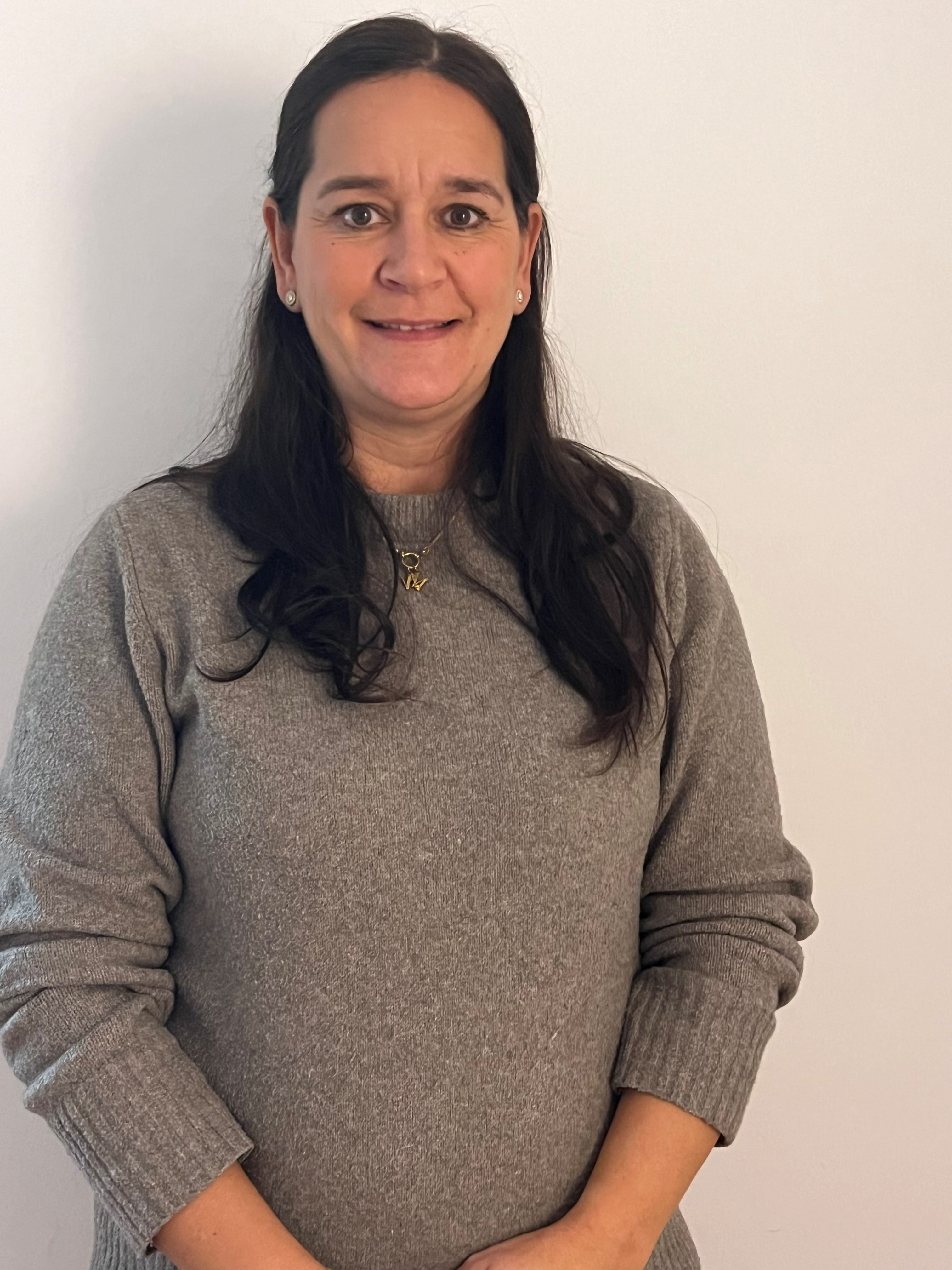 Frau mit grauem Pullover vor weißer Wand