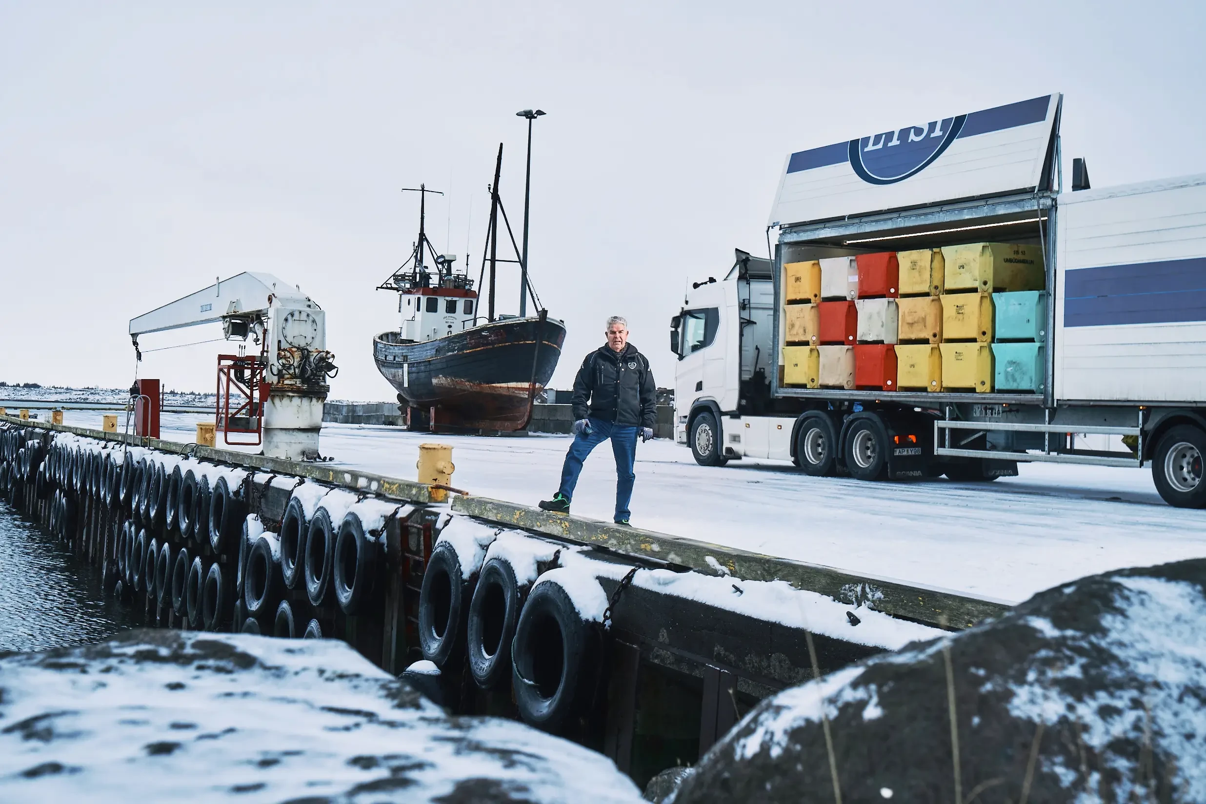 Hafen auf Winglinger Island mit Fischerboot, LKW und gestapelten Fischkisten im Winter