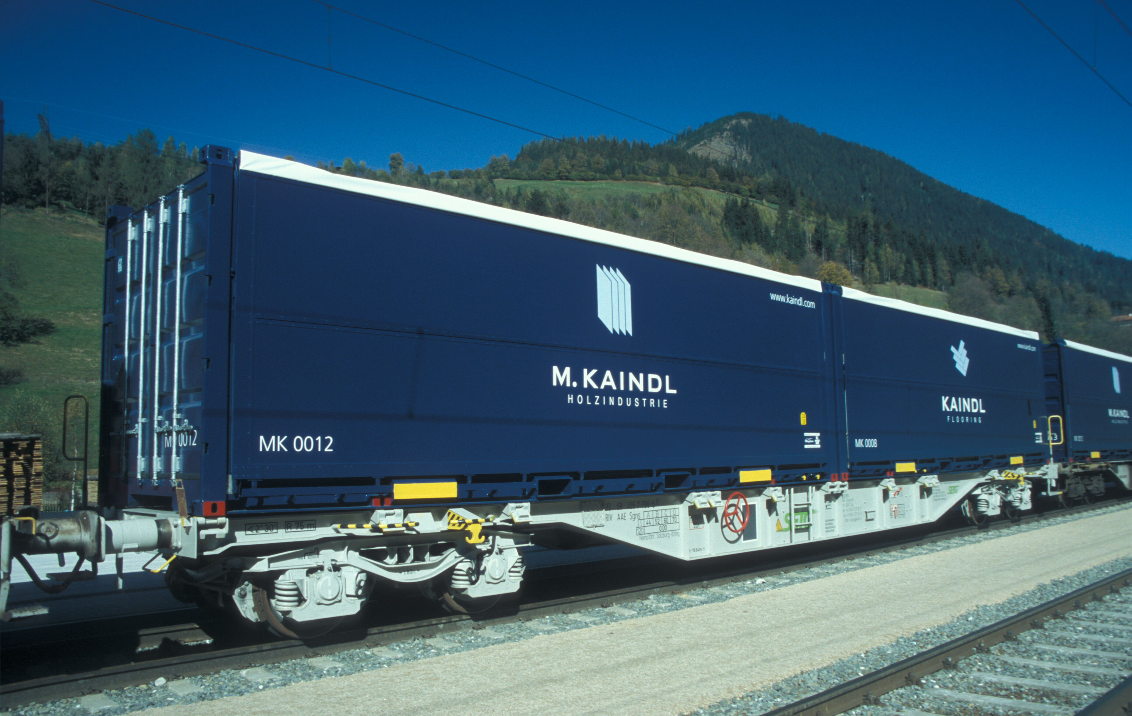 Classic Container Multibox auf Güterzug mit M. Kaindl Holzindustrie Logo vor Alpenlandschaft