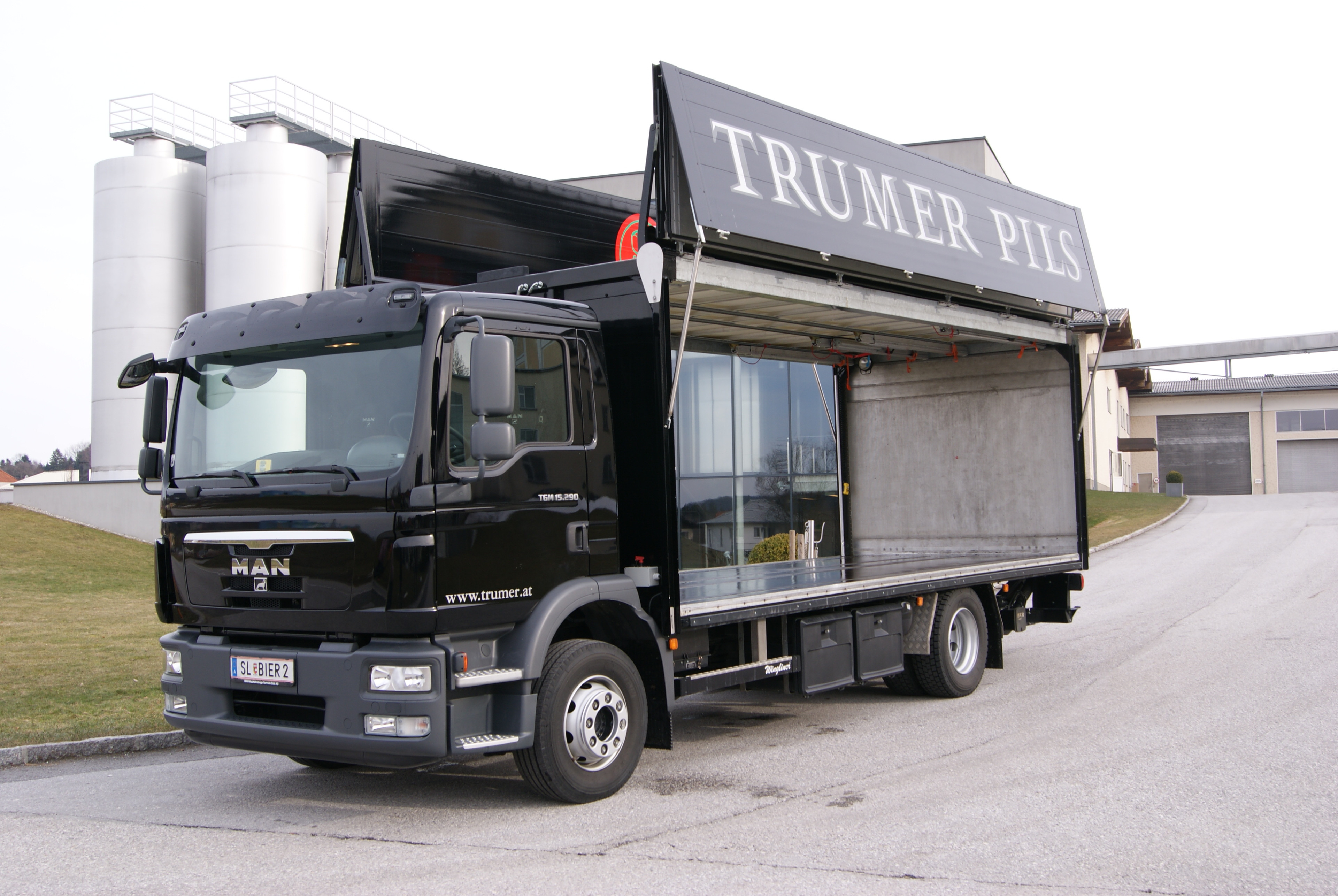 MAN LKW mit geöffneter Seitenklappe und Trumer Pils Werbung