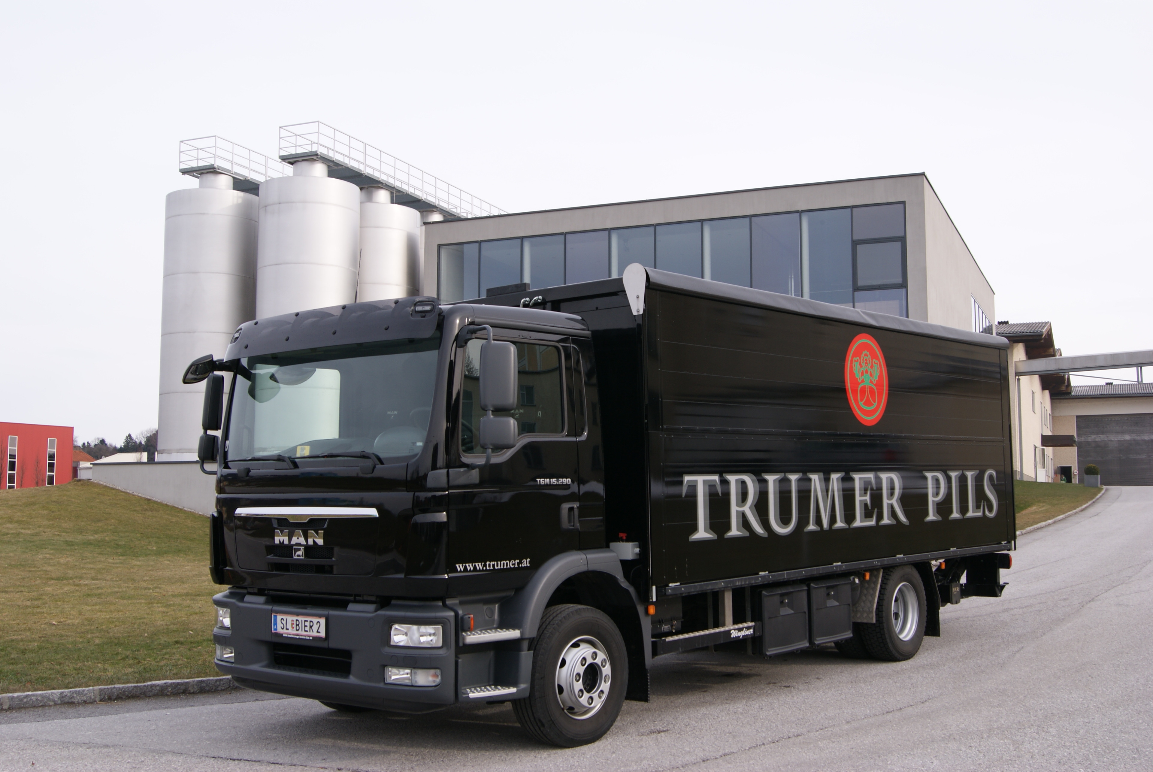 Trumer Pils LKW vor moderner Brauerei mit Edelstahltanks