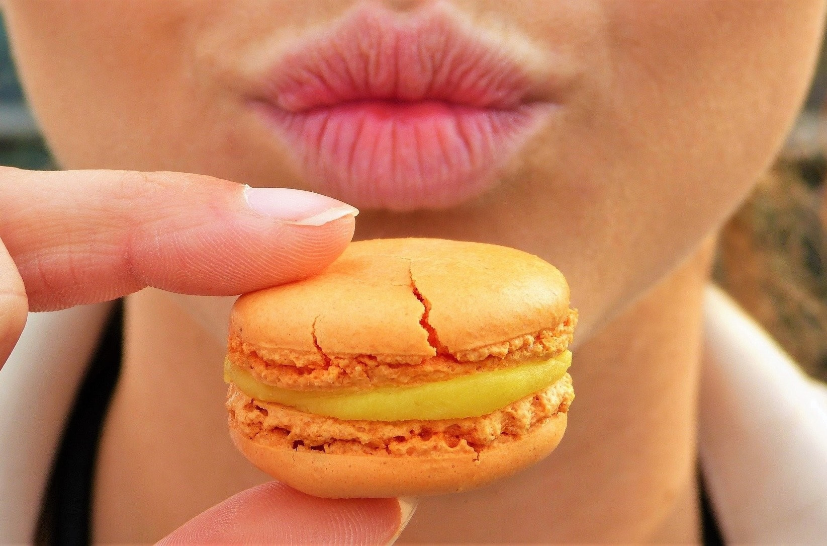 Nahaufnahme eines Macarons vor einem Mund, Symbolbild fr Diabetes und Zuckerkonsum