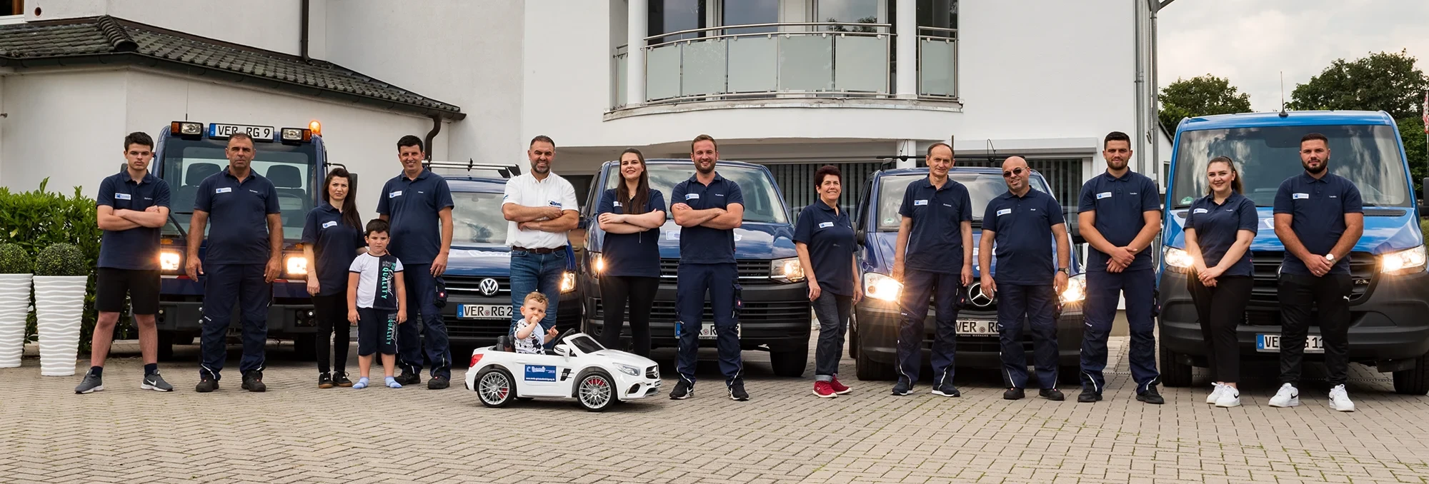 Team vor Firmenfahrzeugen auf der Startseite
