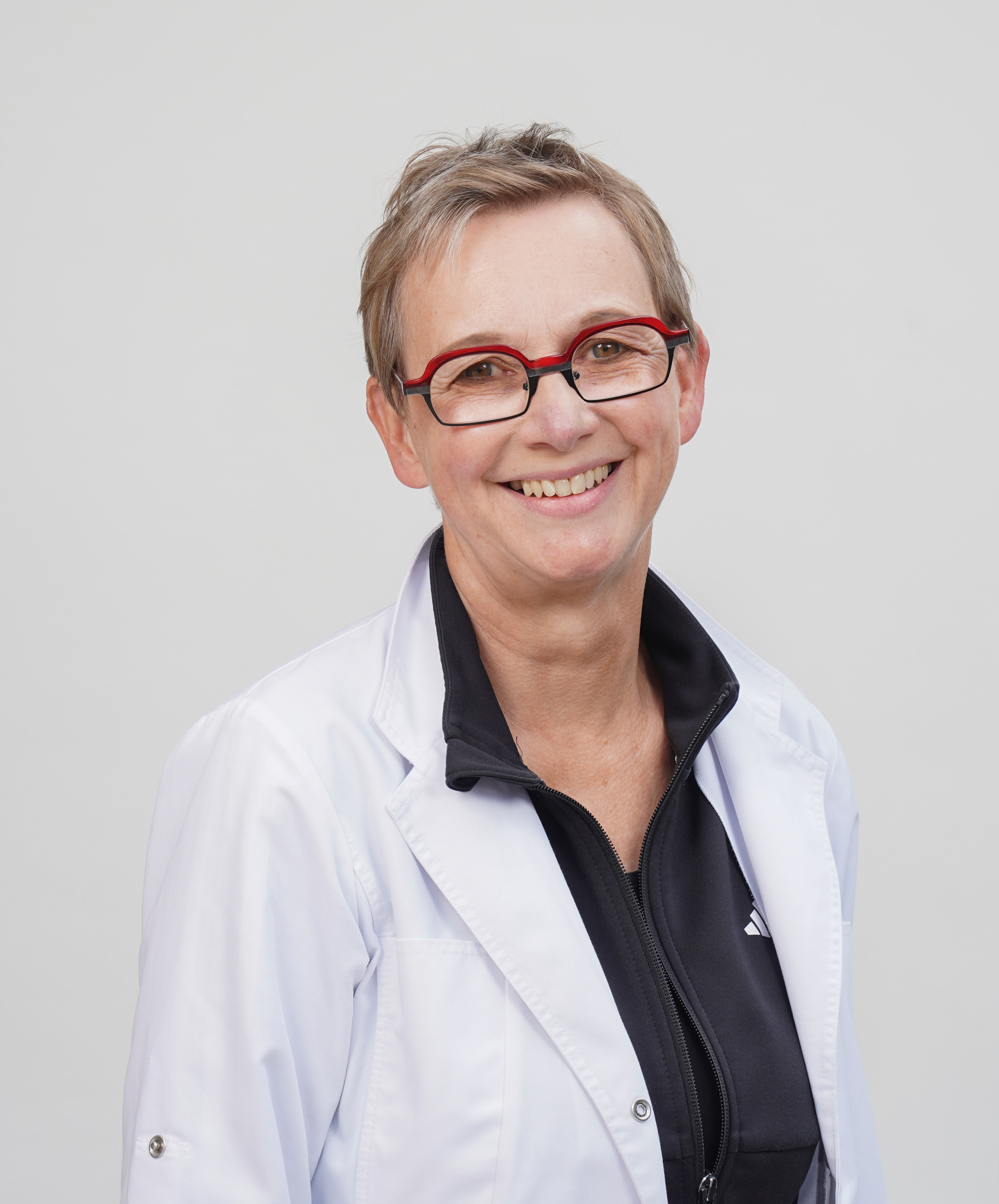Dorothee Meenen im weißen Arztkittel vor neutralem Hintergrund