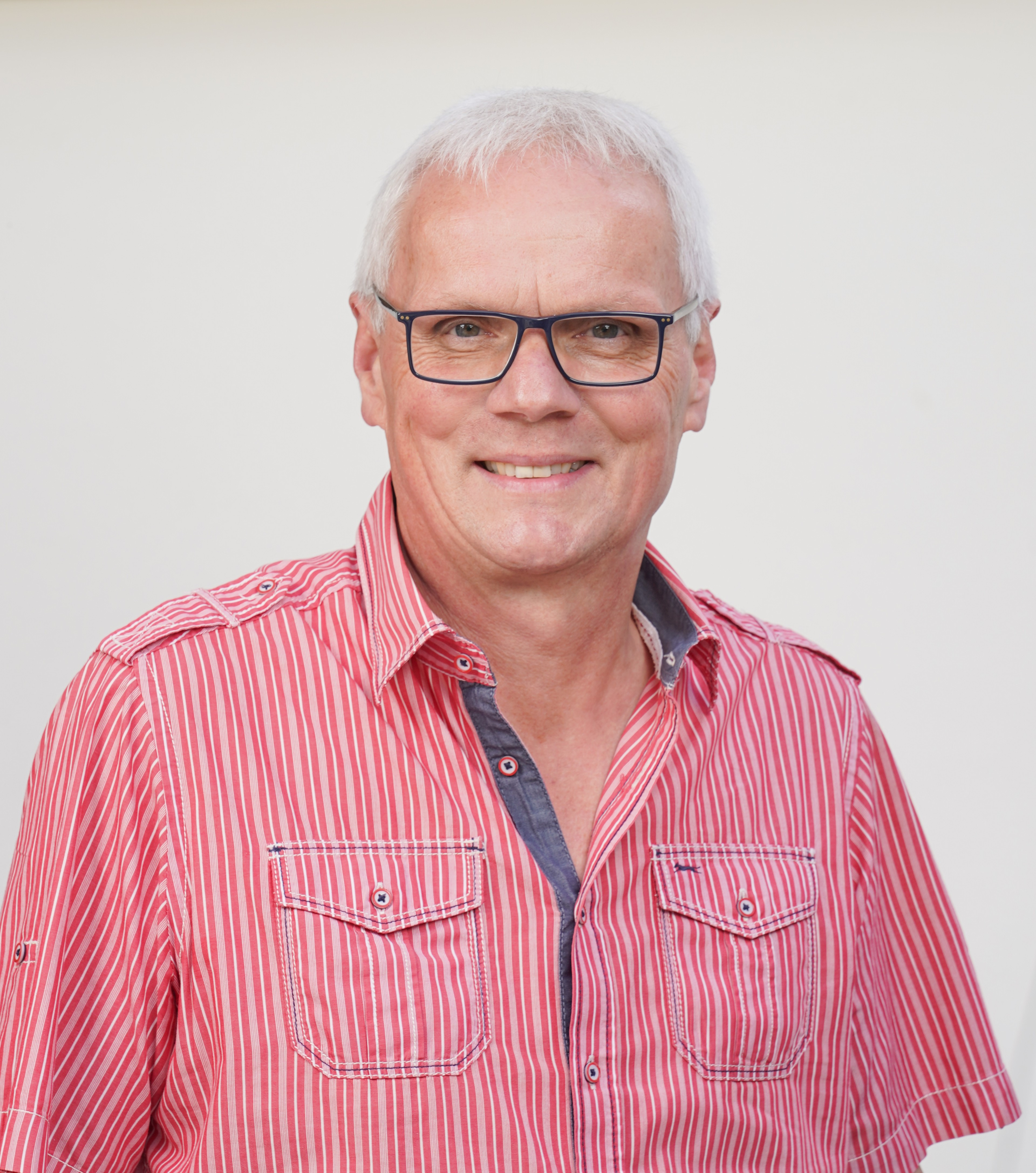 Franz Josef Merkens mit rot-weiß gestreiftem Hemd vor hellem Hintergrund