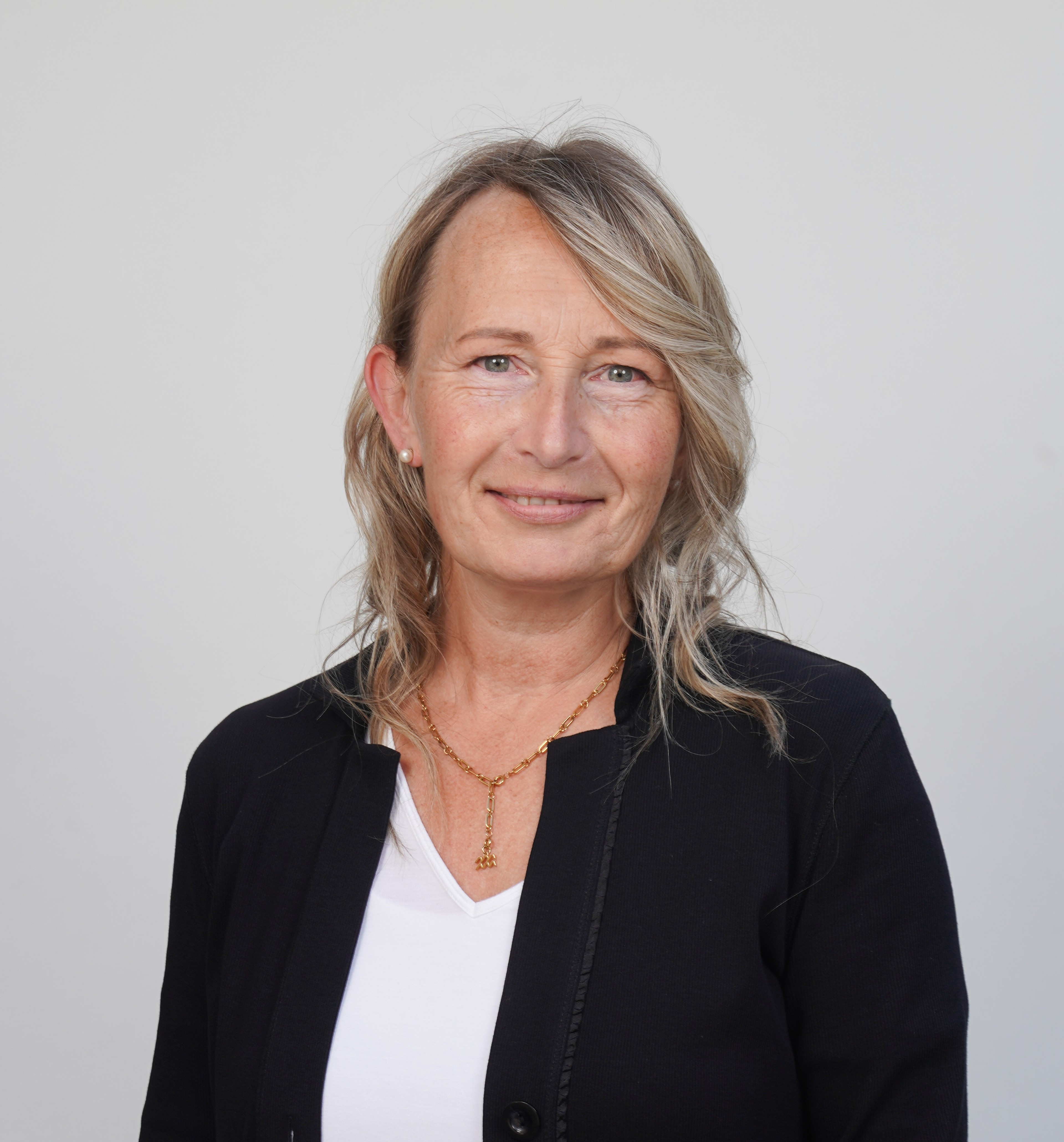 Katharina Linssen im Business-Outfit vor neutralem Hintergrund