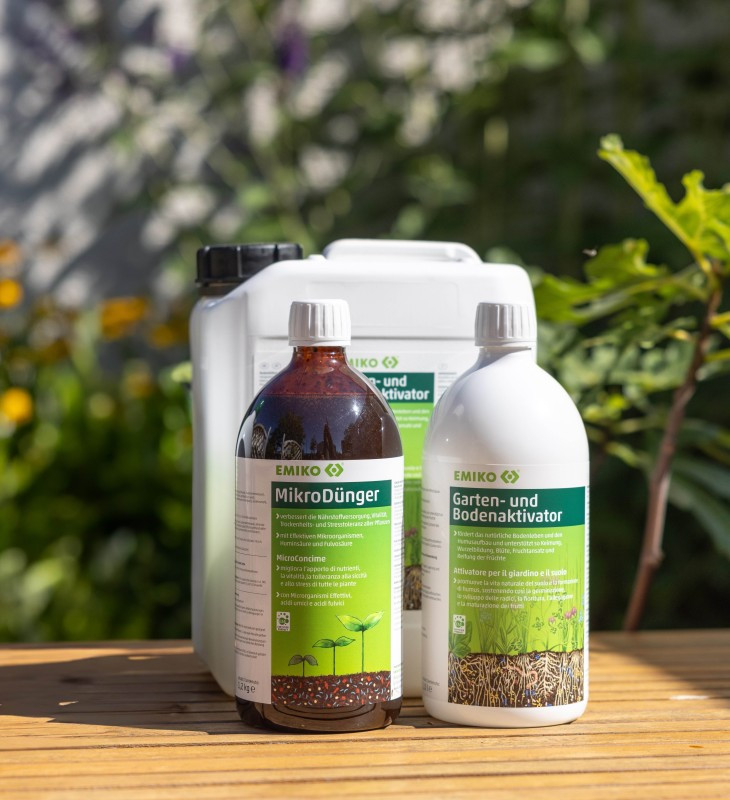 EMIKO MikroDünger und Garten- und Bodenaktivator im Garten auf Holztisch