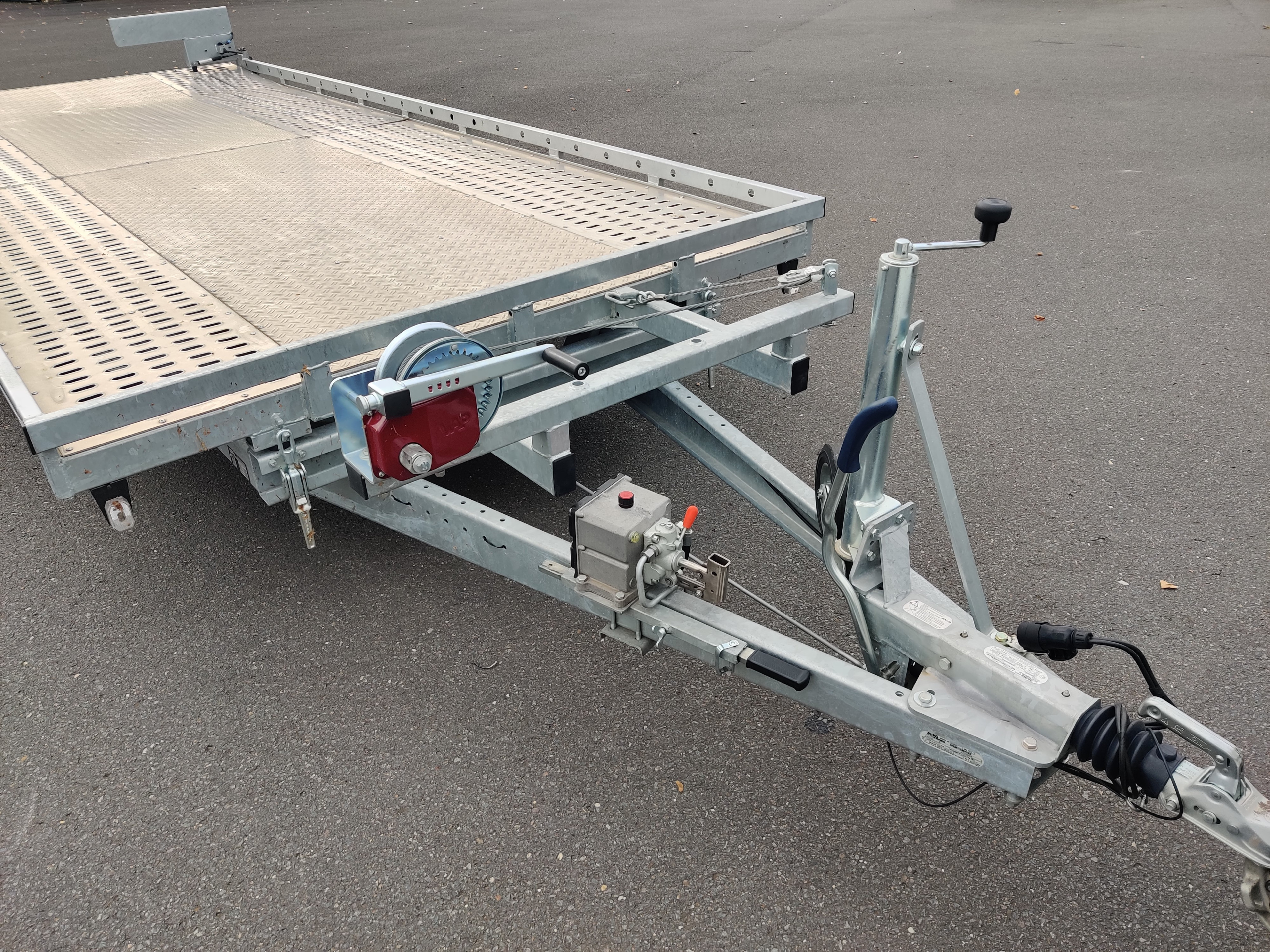 Anhängervermietung: Kippbarer Autotransporter mit Seilwinde auf einem Parkplatz