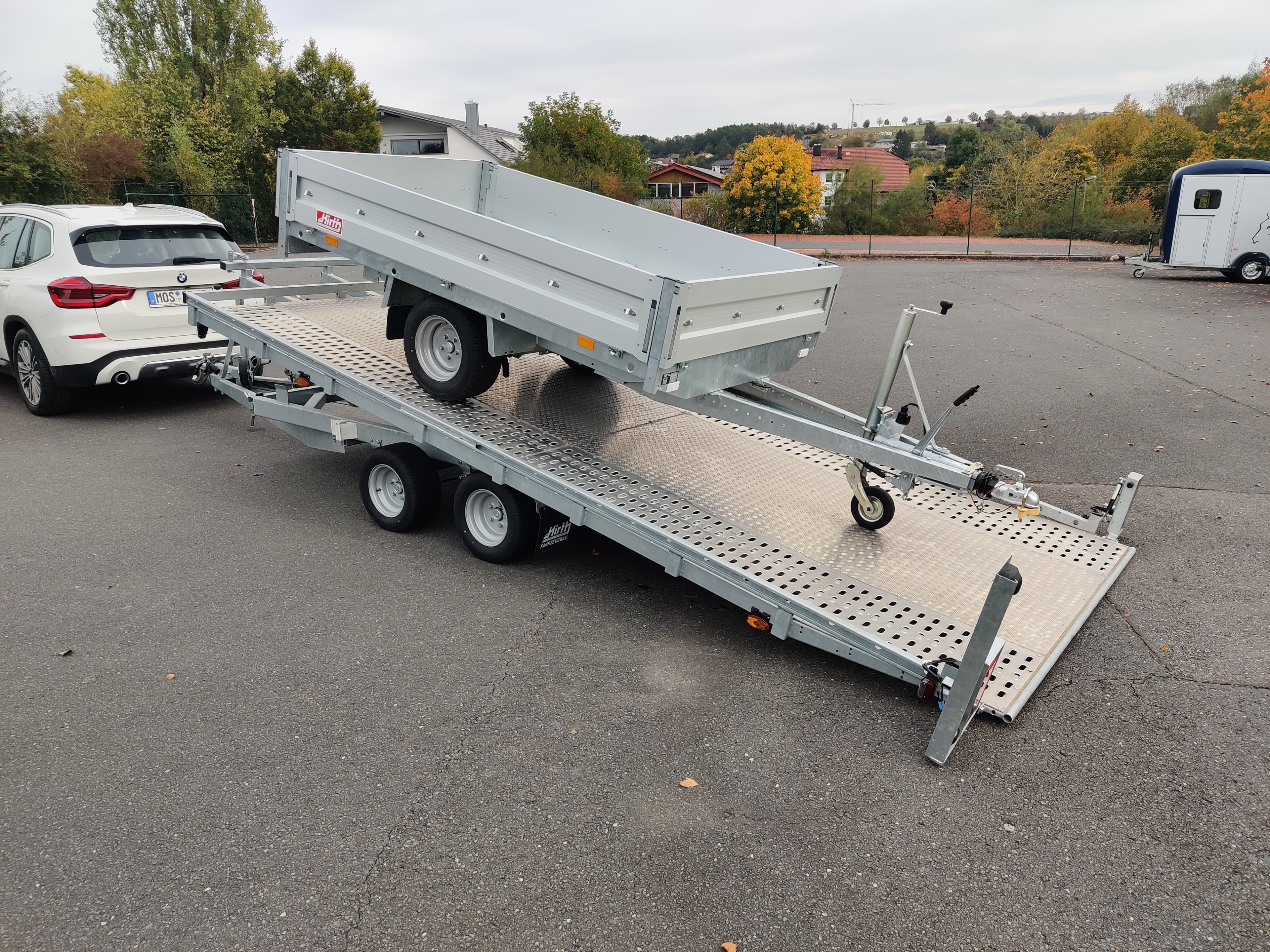 Kippbarer Autotransporter mit Seilwinde von Farmperfekt als Mietanhänger auf einem Parkplatz