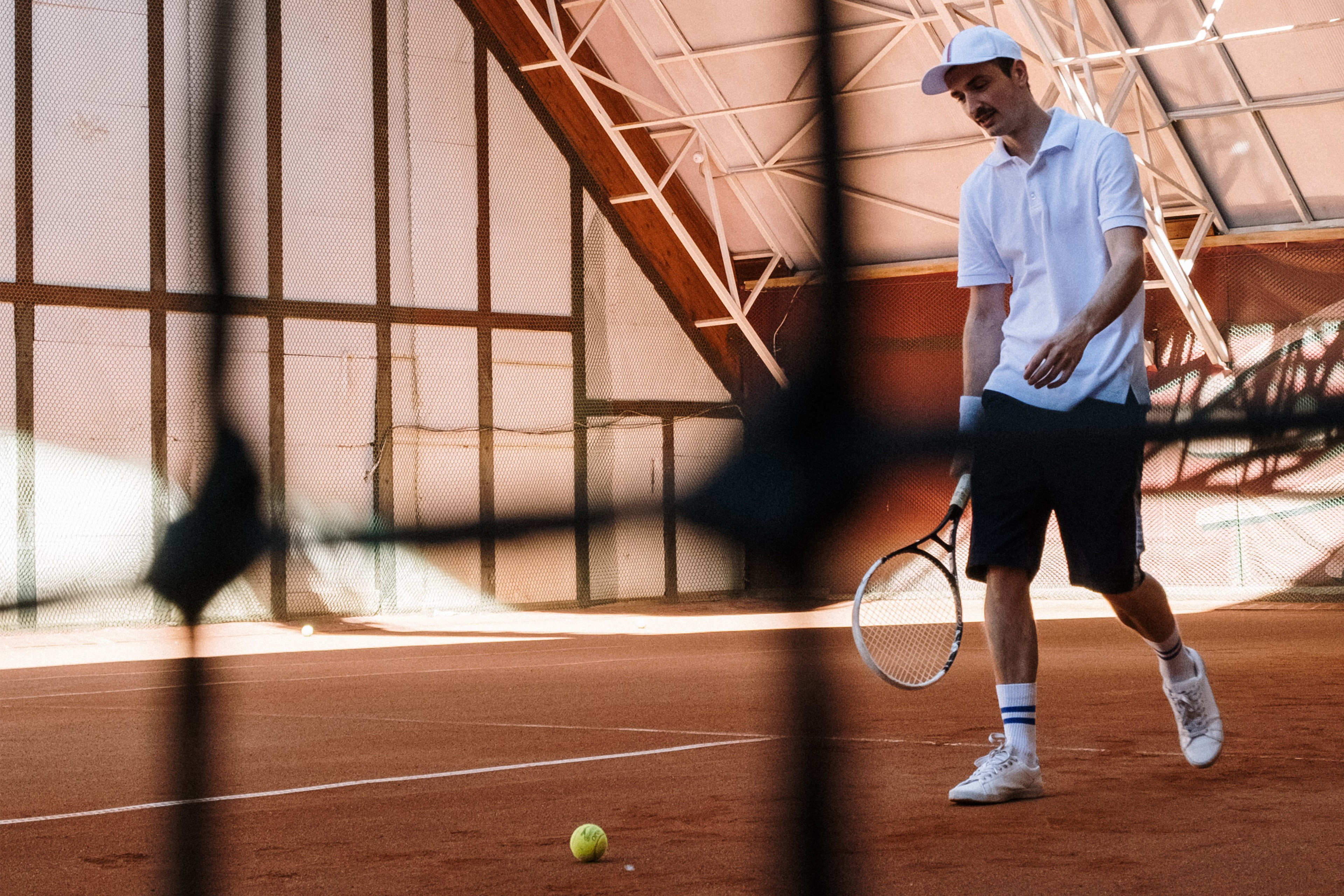Tennisspieler auf einem Sandplatz beim Tennis-Spiel in einer Halle