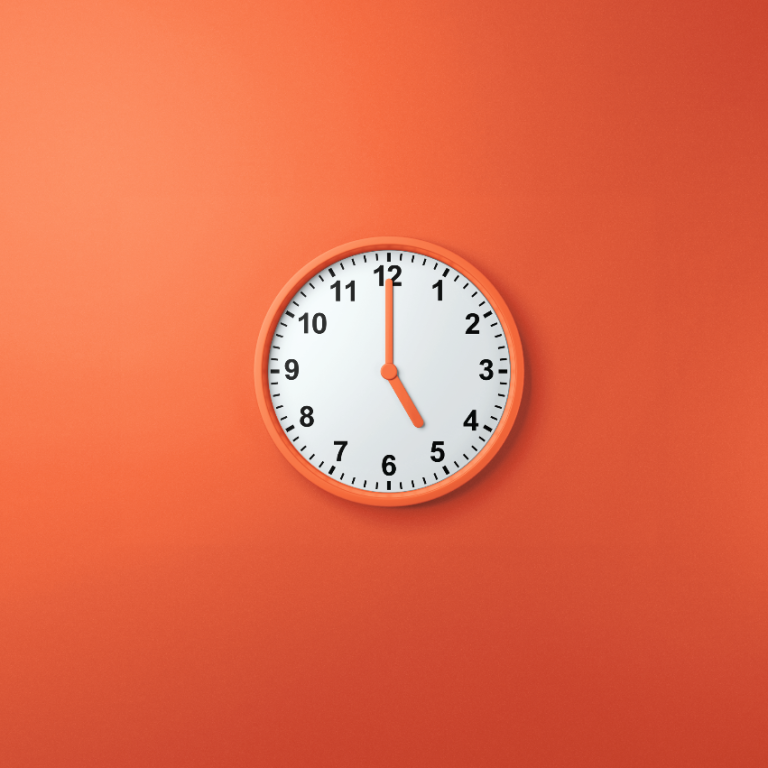 Analoge Wanduhr auf orangefarbenem Hintergrund, zeigt 17:00 Uhr