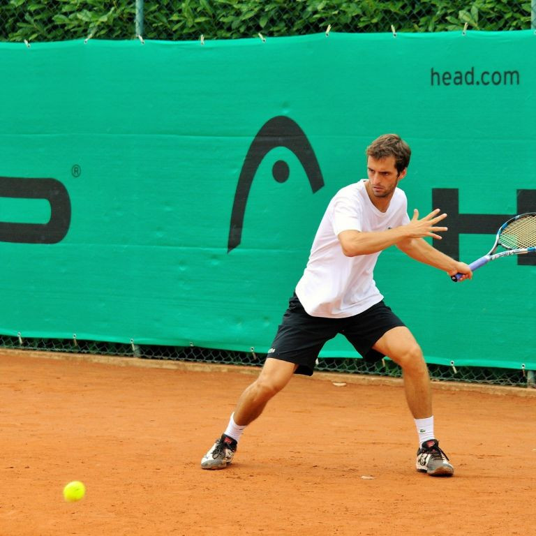Tennisspieler beim Vorhandschlag auf Sandplatz mit Head-Werbebanner im Hintergrund
