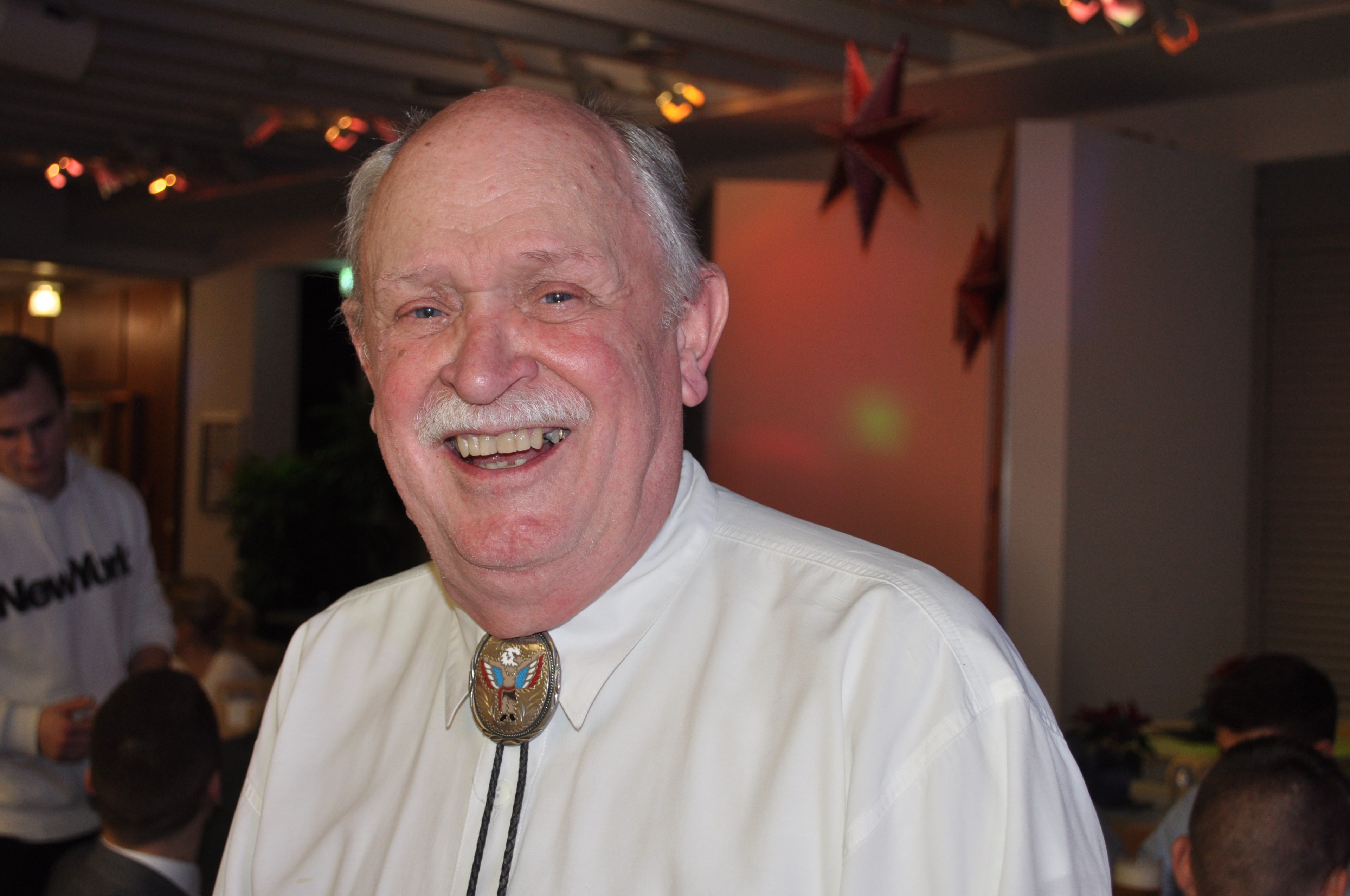 Lachender älterer Mann mit weißem Hemd bei festlichem Anlass