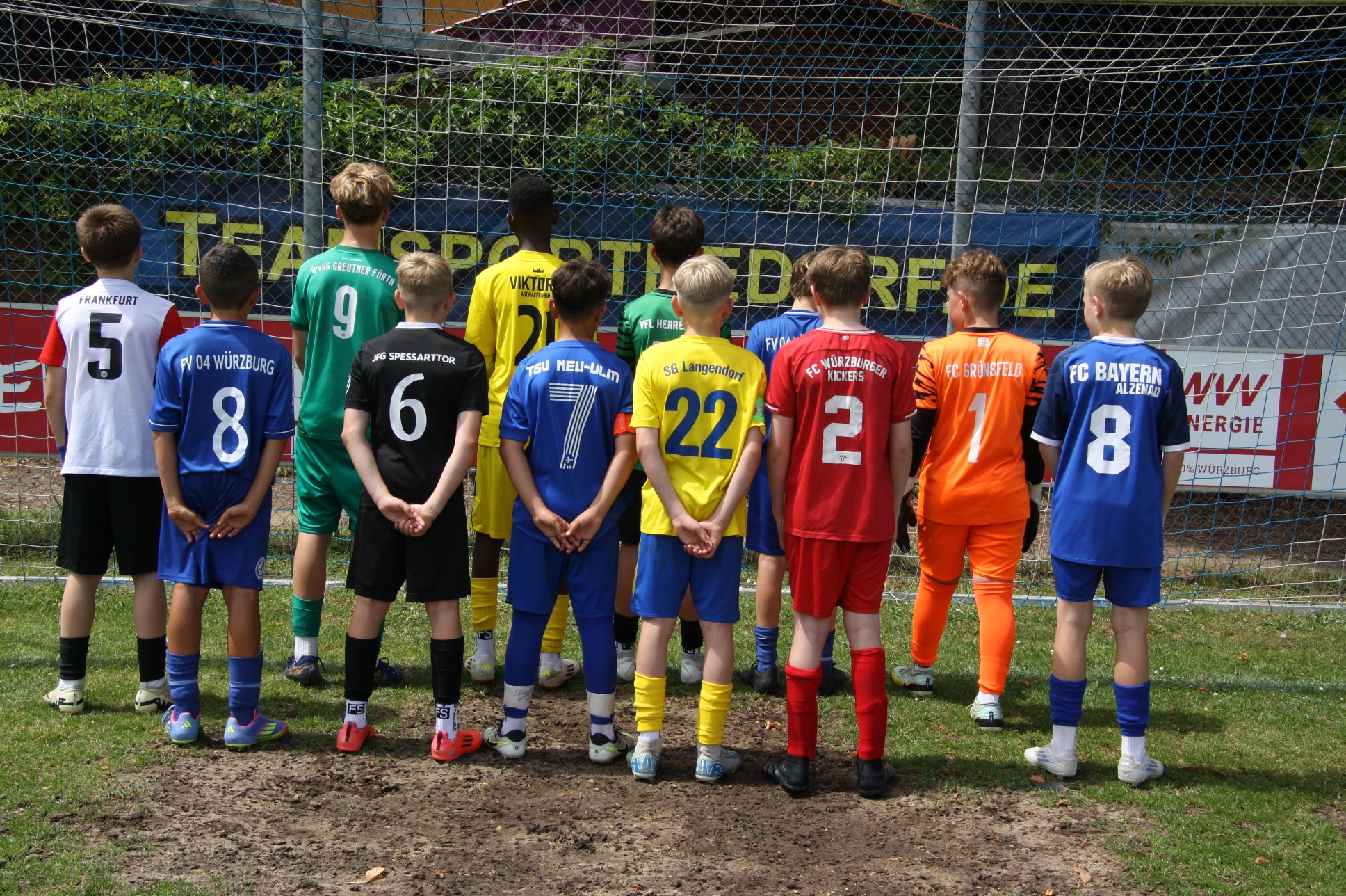 Gruppe von Jugendfußballspielern steht mit dem Rücken zur Kamera vor einem Tor