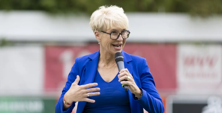 Frau in blauem Blazer spricht mit Mikrofon bei einer Veranstaltung